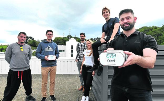 Iñaki Aramburu, en el centro, y Jorge Maylin, a la derecha, muestran las gafas de realidad rodeados del equipo de Oroi. / FÉLIX MORQUECHO